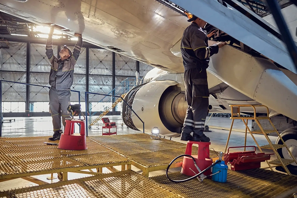 Two men cleaning military aircraft.